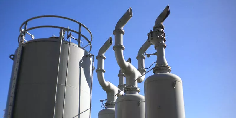 Industrial tanks and pipes under a clear sky