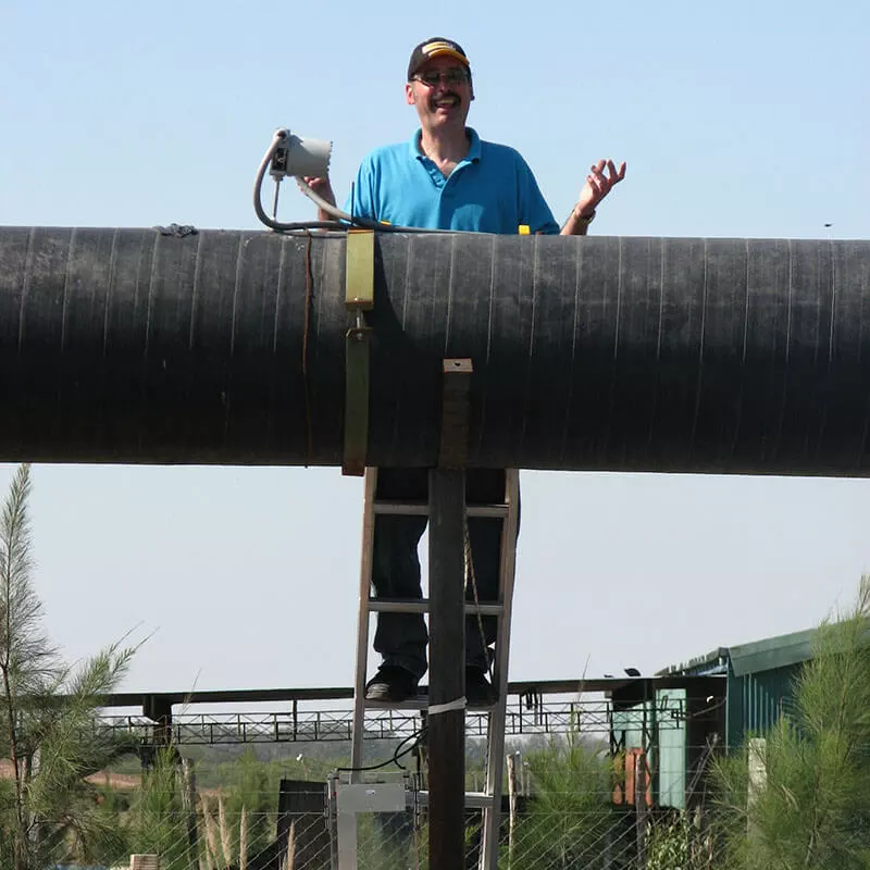 Technician standing behind a large pipe outdoors