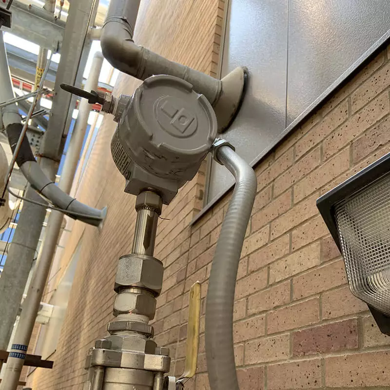 Industrial probe mounted near a brick wall